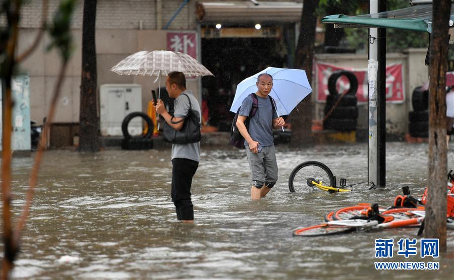 7月24日，在天津市南開區迎水道，路人涉水前行。