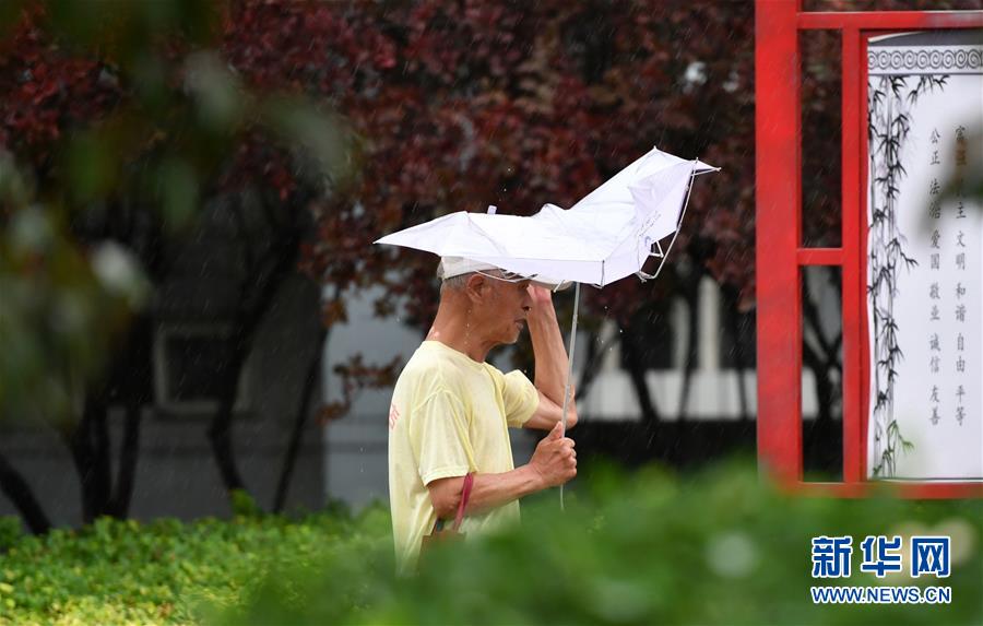 7月24日，在天津市西青區中北大道，一位老者冒雨前行。
