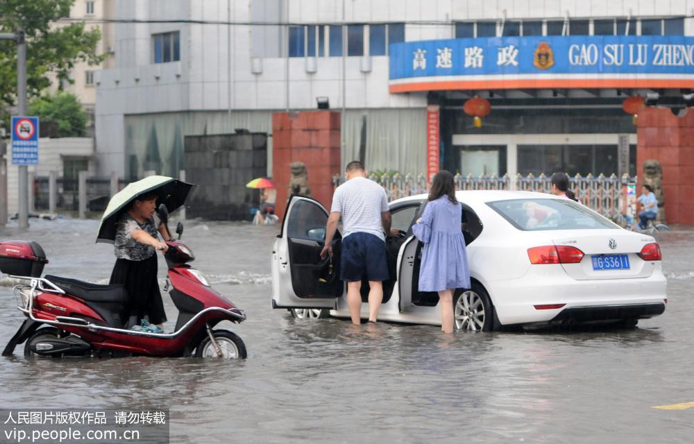 8月4日，江西九江市街頭，市民在積水路段涉水推車前行。