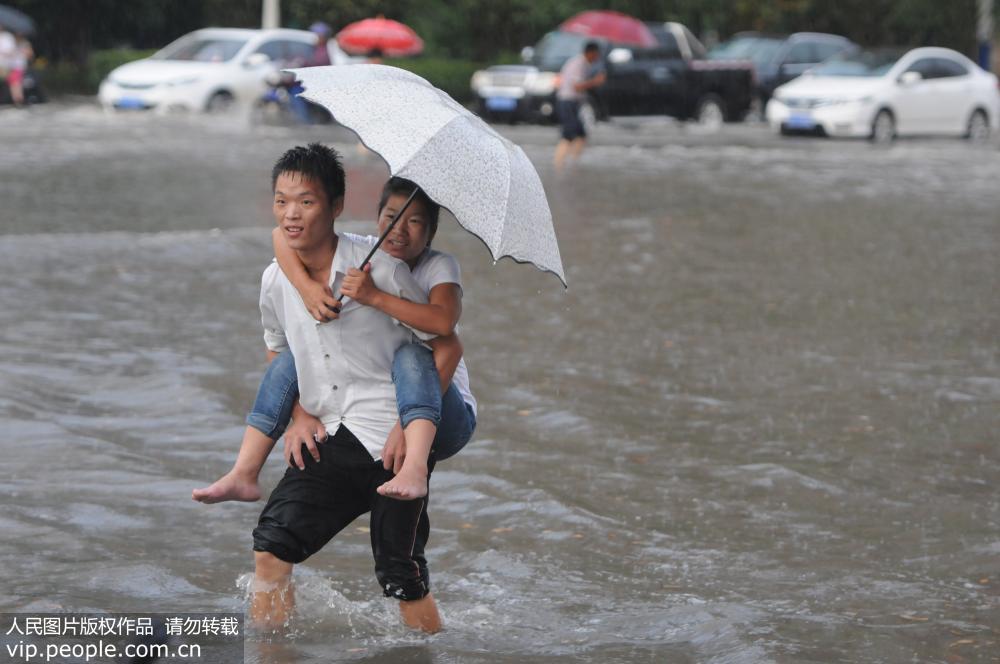8月4日，江西九江市街頭，市民在積水路段涉水艱難前行。