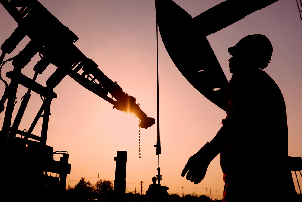 華東石油局撈油班職工在夕陽下放井架。