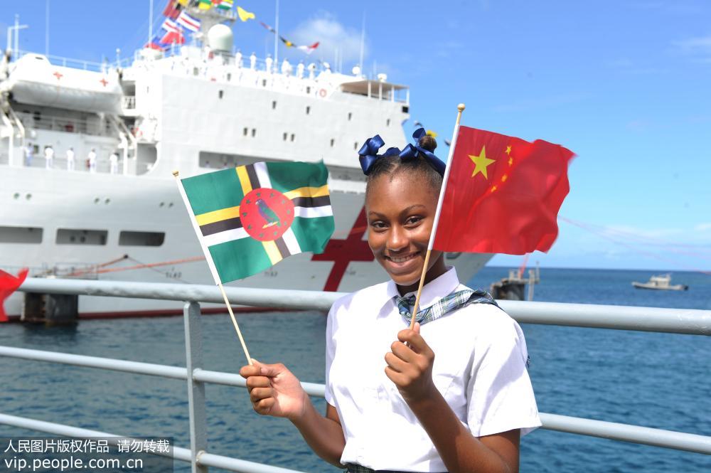 10月12日，多米尼克首都羅索港，當地學生揮動多中兩國國旗熱烈歡迎中國海軍和平方舟醫院船首次到訪。