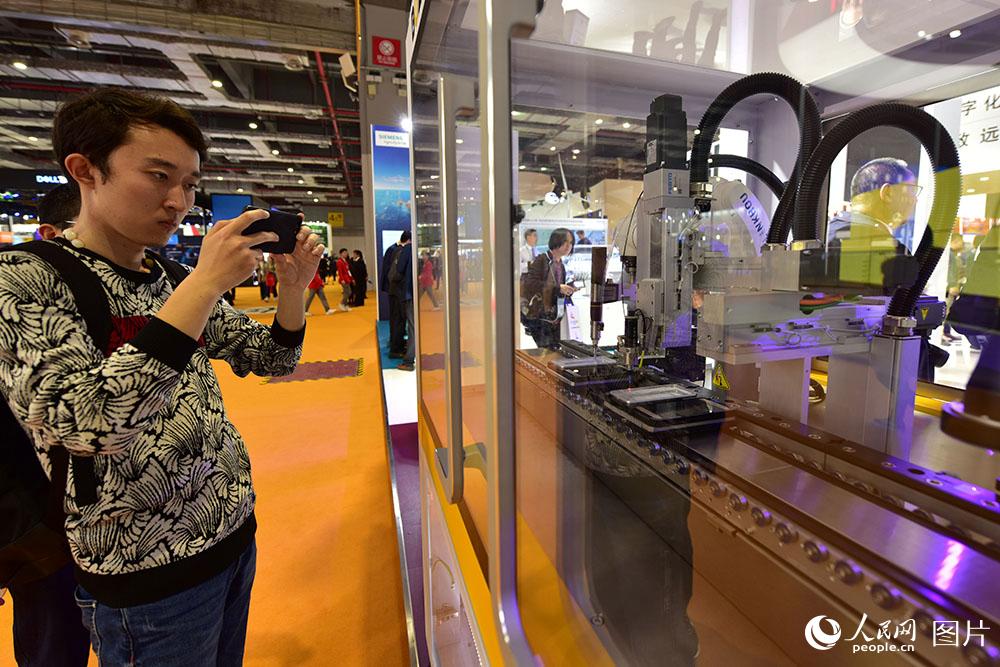 11月5日，在进博会西门子展台，参观者正用手机拍摄手机屏幕的安装检测过程。（人民网记者 翁奇羽 摄）
