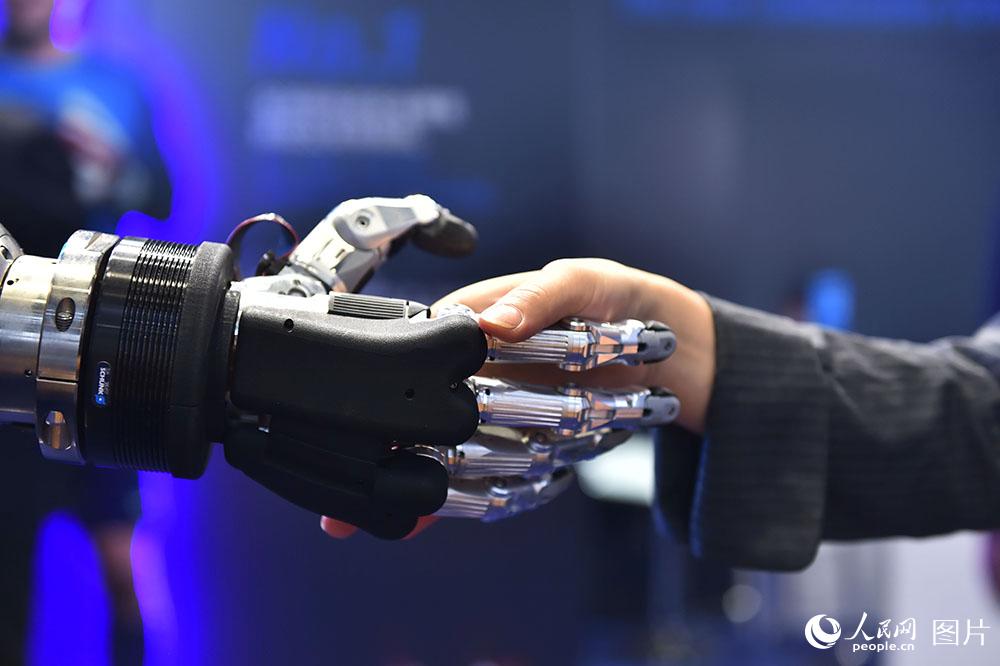 11月6日，在进博会雄克公司展台，参观者正试着和仿人五指机械手握手。（人民网记者 翁奇羽 摄）