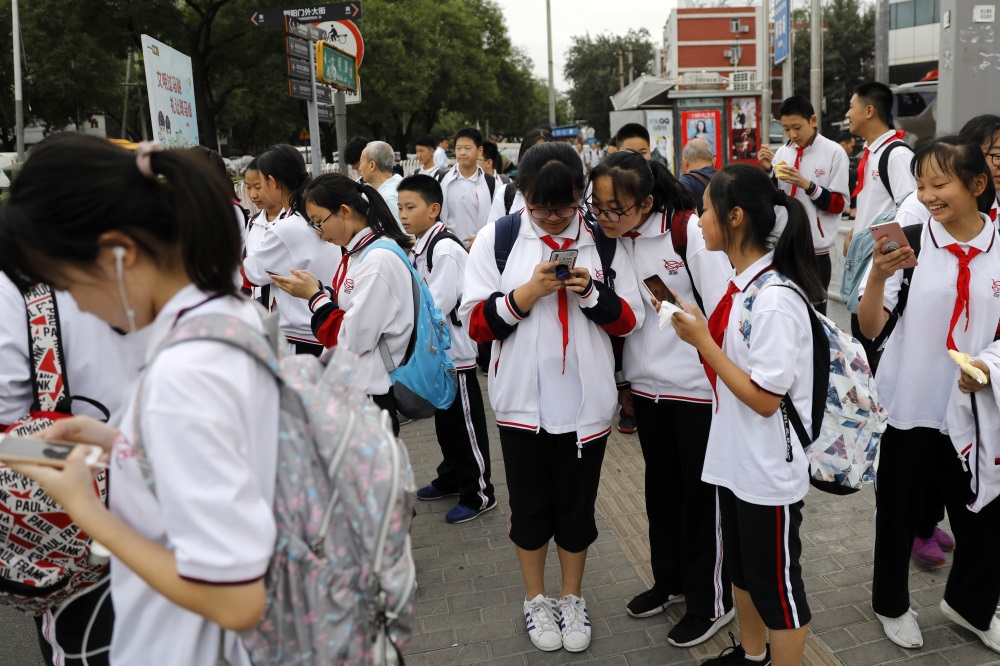 2018年9月18日，北京市朝陽區東大橋，放學的孩子們在等待過馬路的間隙查看手機信息。吳宏（中國）攝