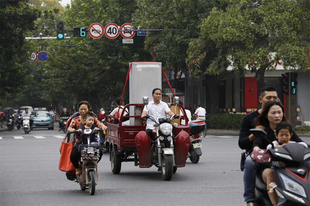 2018年9月22日，江蘇省揚州市國慶路，一騎電動車男子在搬運冰箱。  張啟琴（中國）攝