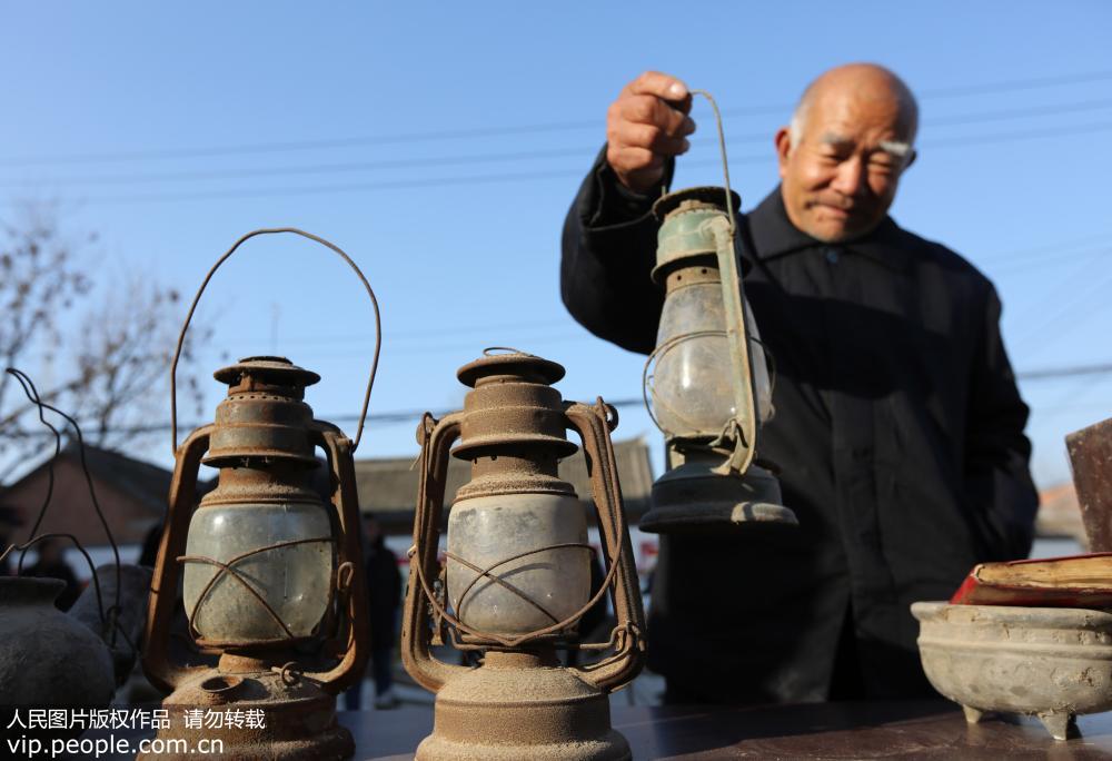 12月16日，一位老人在河南省武陟縣小董鄉喬庄村觀看展出的油燈。