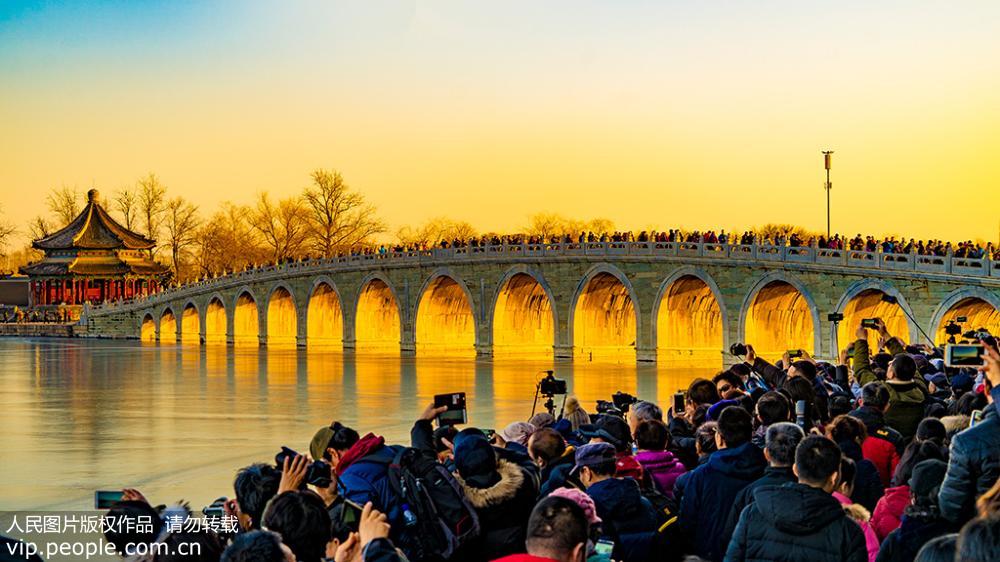 12月18日，北京頤和園，攝影愛好者們在十七孔橋邊拍攝“金光穿洞”美景。