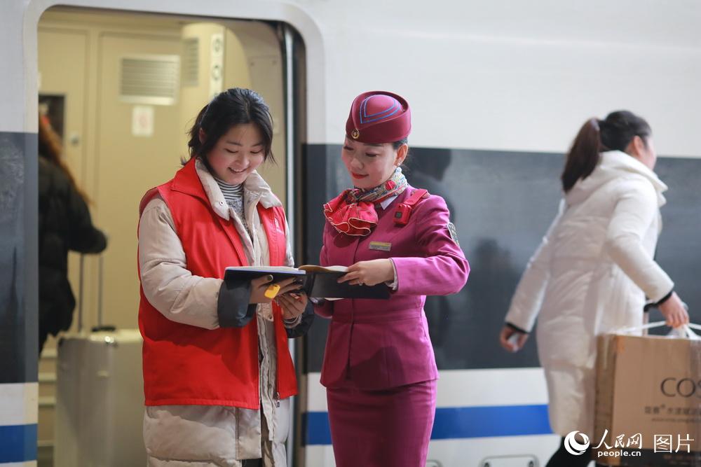 刘玉婷和志愿者在成都东站的站台上办理残疾人旅客重点交接手续。