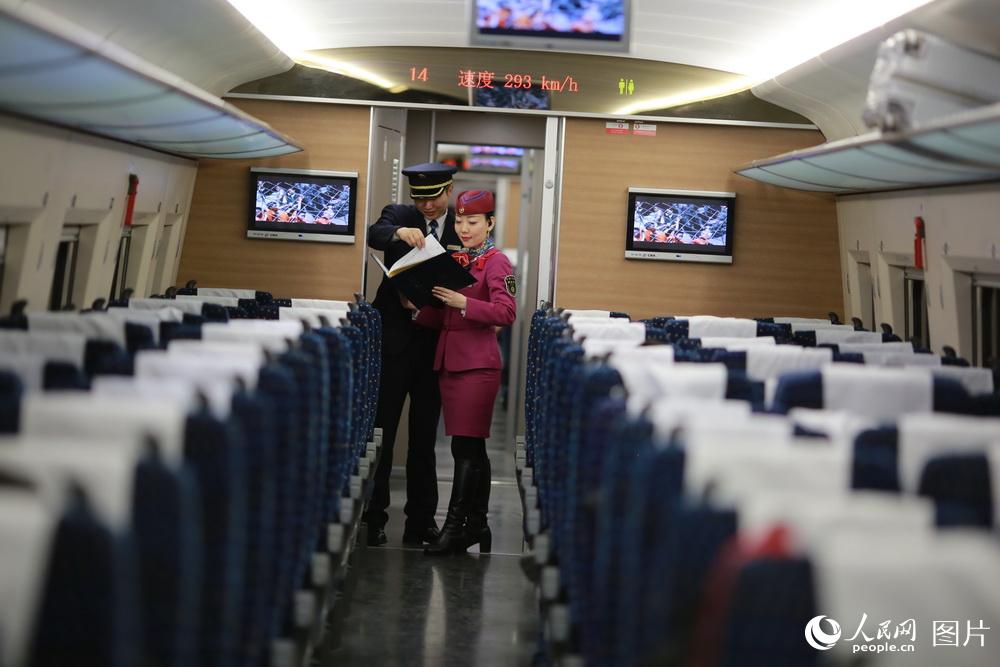 列车长刘玉婷和实习车长在车厢连接处进行工作交流。