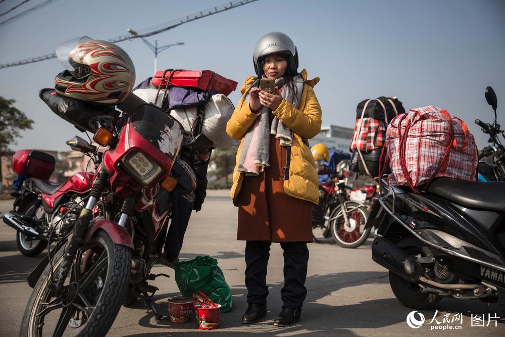 2019年1月24日，廣東佛山。蛟塘驛站，一位坐摩托車累了的女務工者玩著手機，她在補給站裡可以休息片刻。