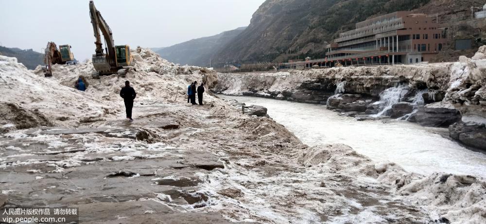 1月30日，山西省吉縣黃河壺口瀑布景區工作人員用挖掘機鏟除冰雪。