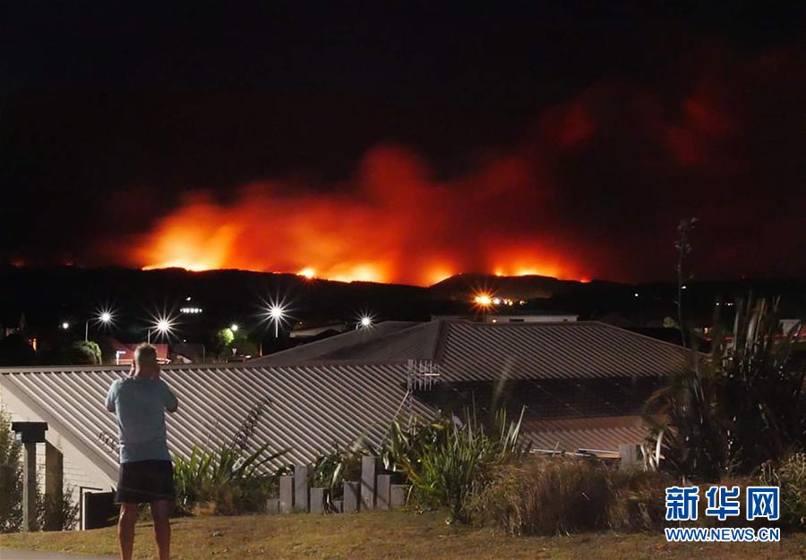 2月6日，在新西蘭南島北部，一名居民拍攝火情。  新華社發