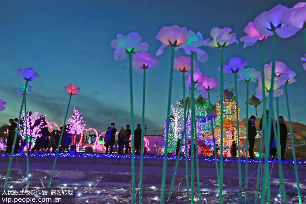 2月15日，游客在新疆哈密街頭參觀燈光秀景觀。