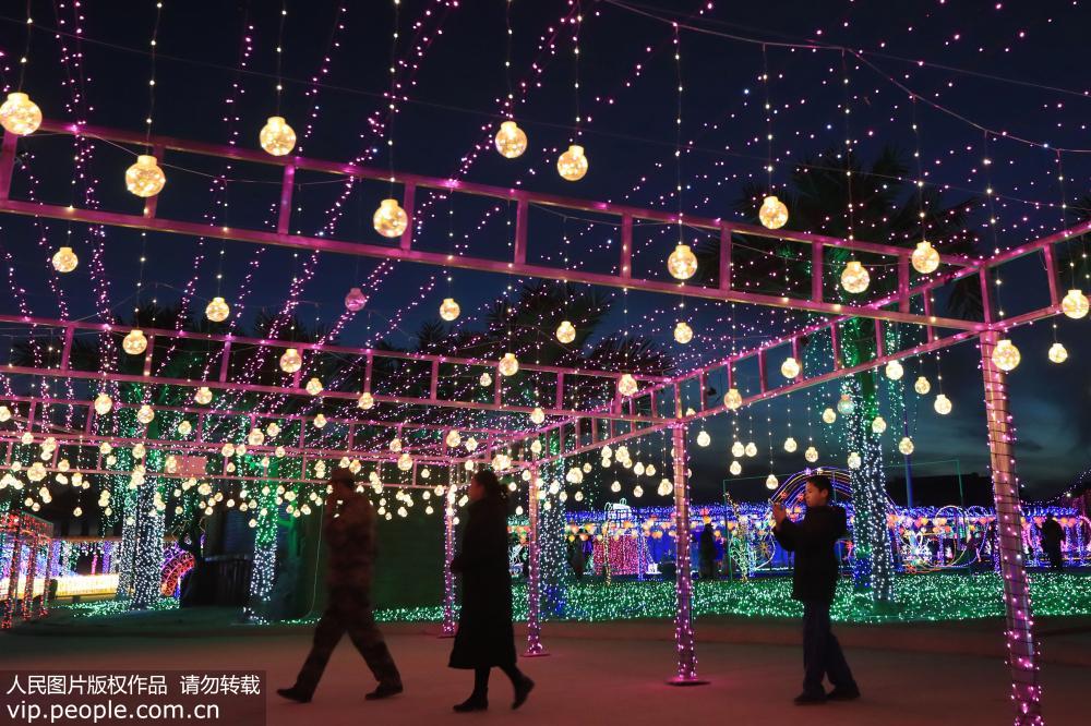 2月15日，游客在新疆哈密街頭參觀燈光秀景觀。