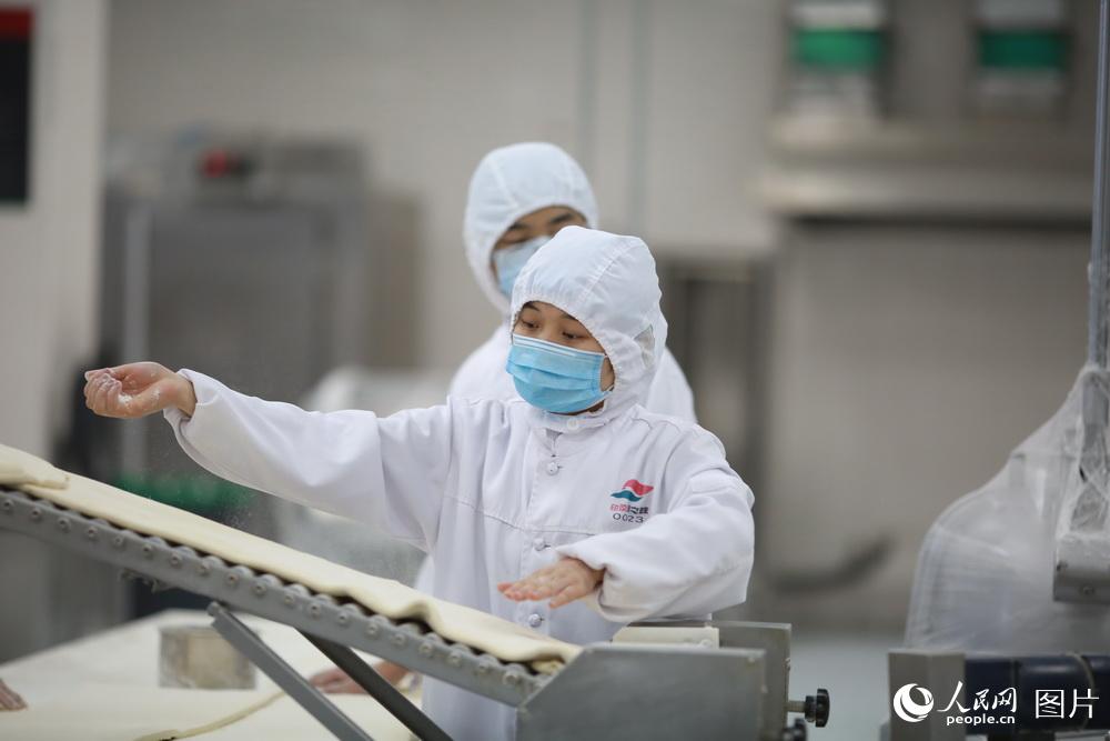 面點加工區工作人員正在對面片上撒面粉，防止生產過程中粘連。蘇志剛 攝影