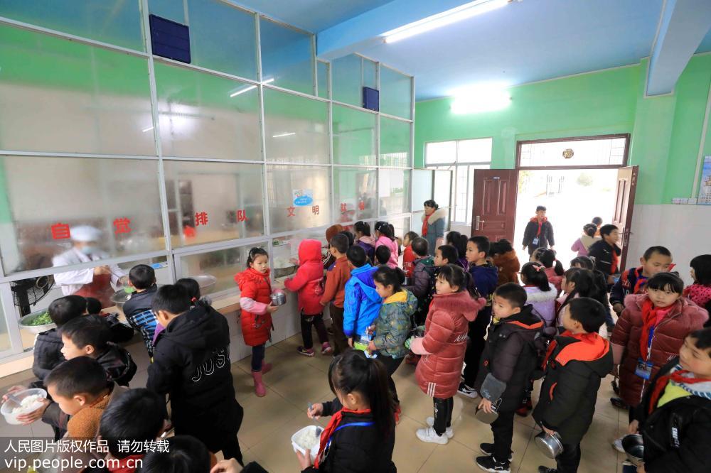 2月18日，在广西柳州市融安县大坡乡岗伟村小学，学生们在排队领取“免费午餐”。
