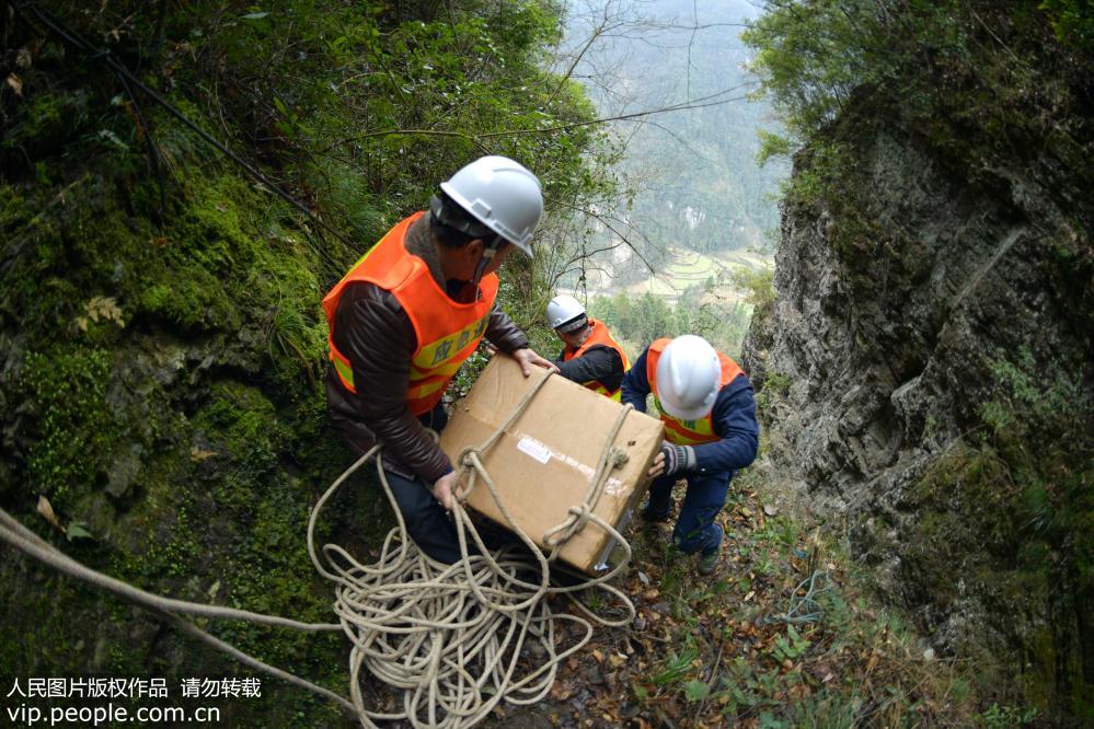 2019年2月22日，工人在往湖北省宣恩县两溪河村借助绳索往山顶运送通讯铁塔建设设备。