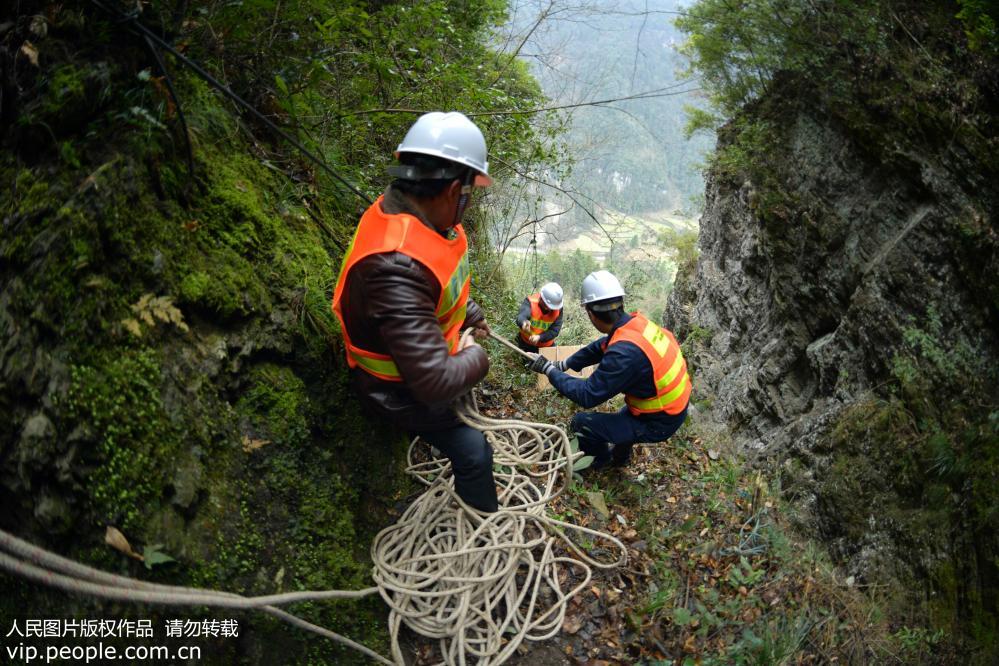 2019年2月22日，工人在湖北省宣恩县两溪河村搭建通往山顶的绳索通道。
