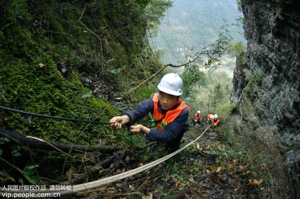 2019年2月22日，工人在往湖北省宣恩县两溪河村借助绳索往山顶运送通讯铁塔建设设备。