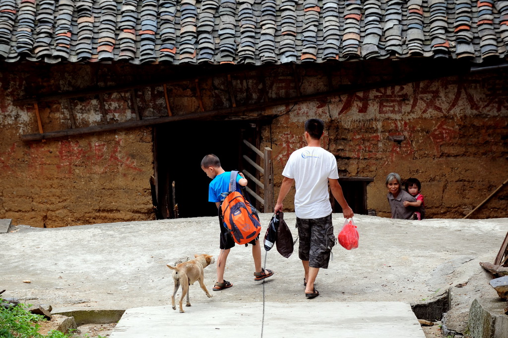 2013年7月23日，龍飛聯的侄子龍杰（左）回到村裡過暑假，家裡的狗對這位長年在外讀書的小孩感到陌生。 新華社記者 黃孝邦 攝