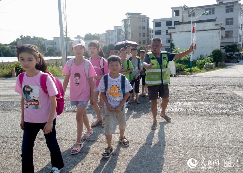 李丙味帶領孩子們穿過馬路。 邱順  攝