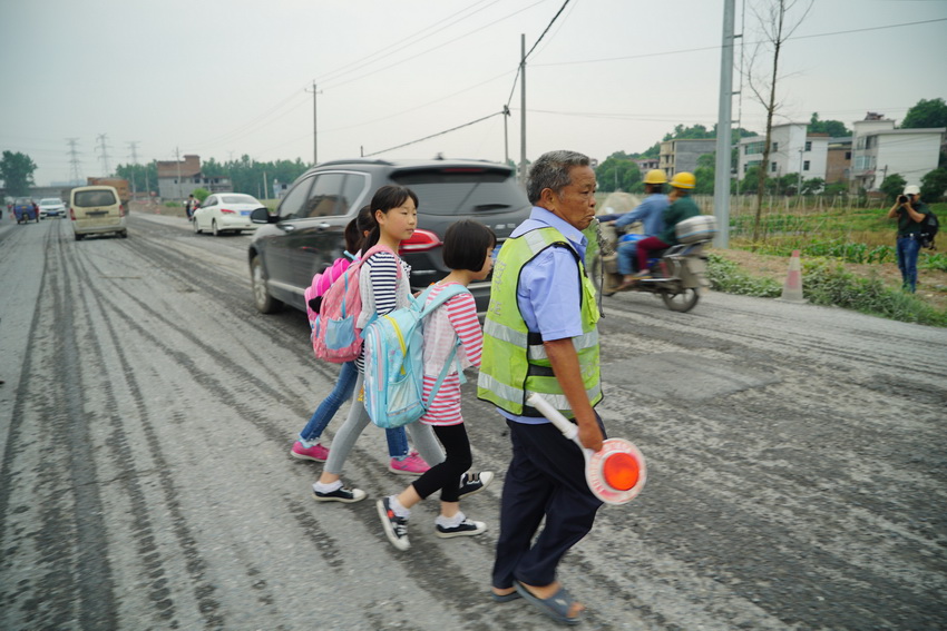 李丙味帶領孩子們穿過馬路。新華社記者 周密 攝