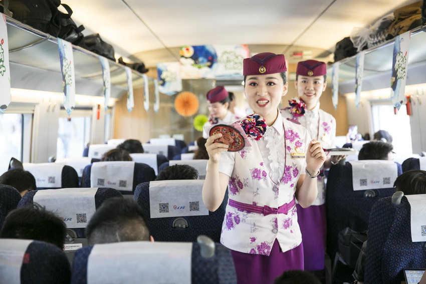 6月5日，在成都东开往昆明南的G2885次高铁上，成都客运段高铁乘务员正在邀请旅客参加“粽”情端午主题活动。