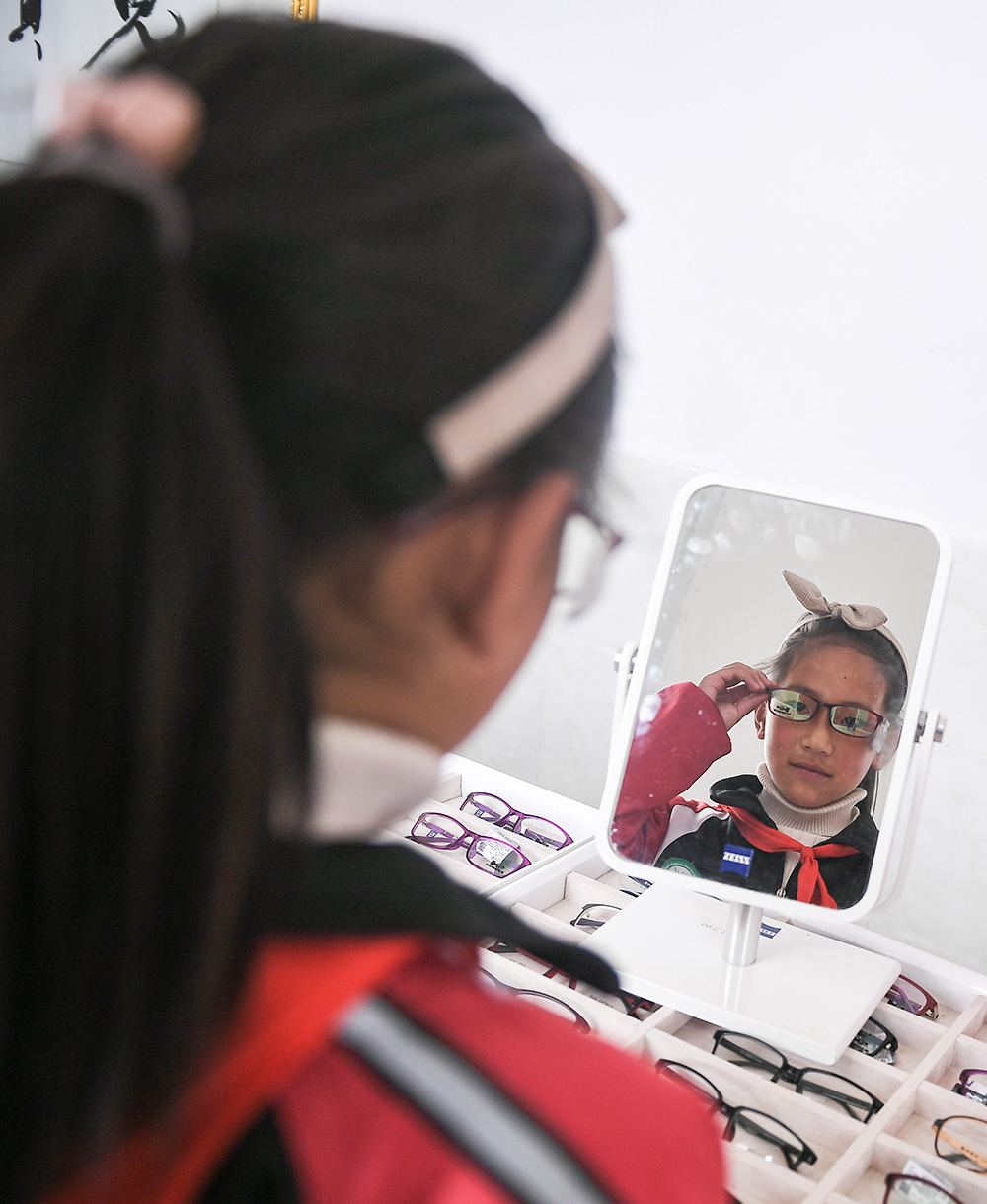 6月17日，在若尔盖县中学，扎西旺姆在挑选镜框。