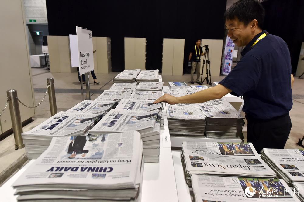 6月27日，G20大阪峰會新聞中心，記者正在領取報紙。（人民網記者 翁奇羽 攝）