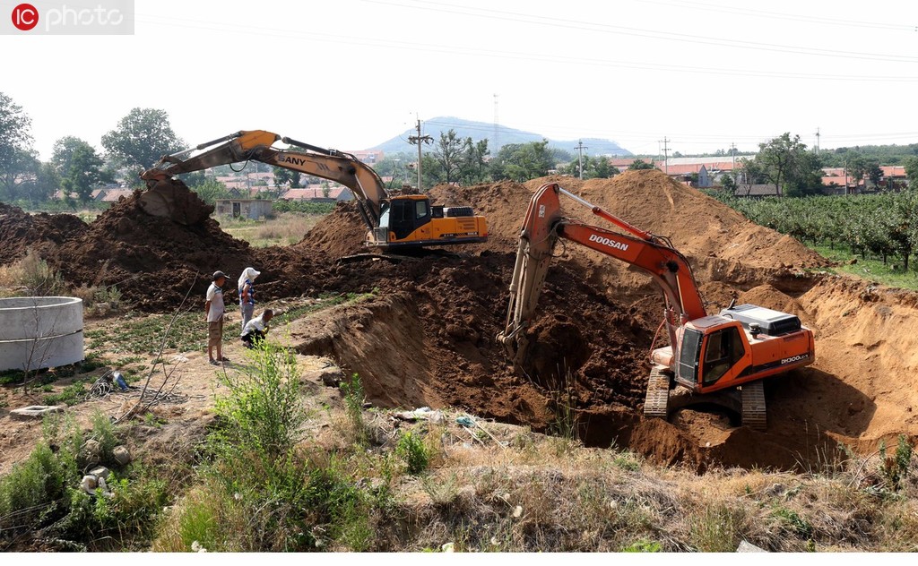 6月27日，在山東省蓬萊市南王街道魏庄村農民在干涸的河邊用機械挖掘大口井取水抗旱。