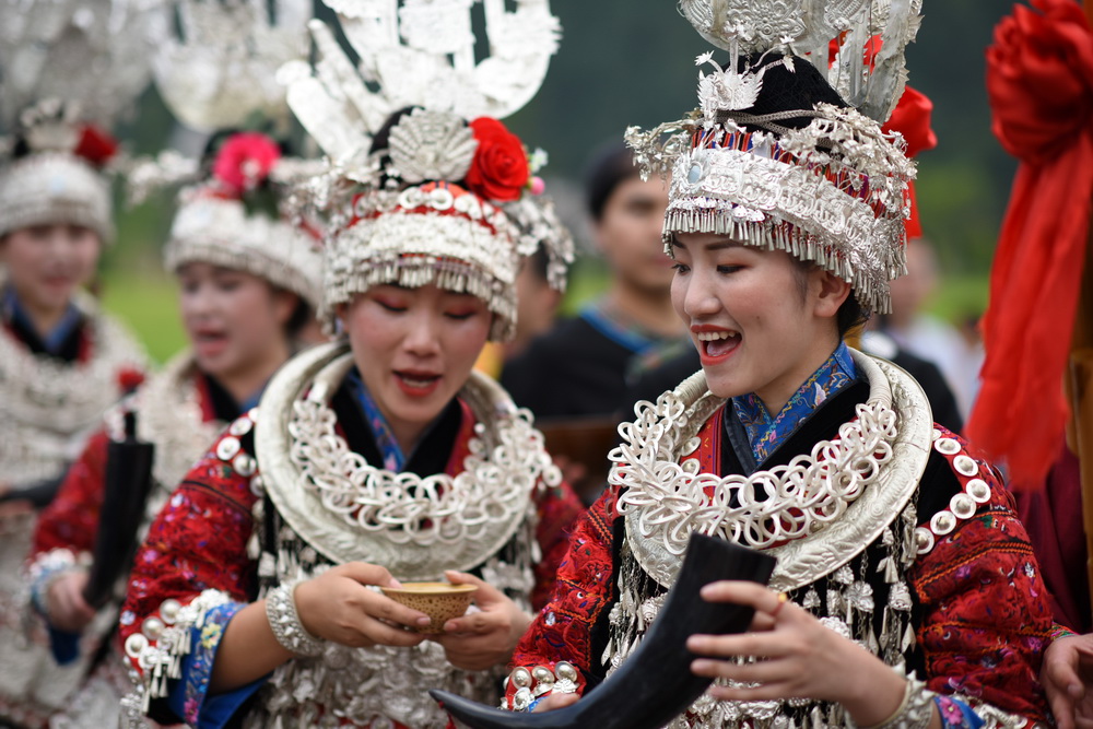 6月27日，在貴州省台江縣苗族獨木龍舟節上，苗族姑娘給來賓敬牛角酒。