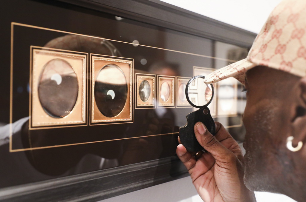 7月1日，在美国纽约大都会博物馆，参观者观看银版摄影法拍摄的日食。 新华社记者 王迎 摄