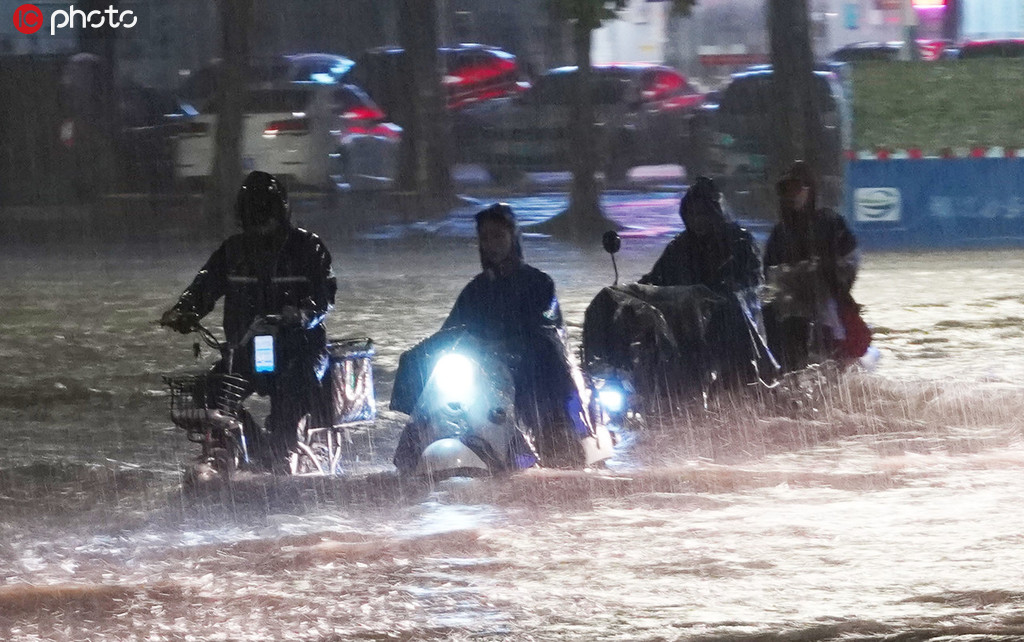 市民駕駛電動車冒雨從南寧市高新區積水嚴重的科德新苑路口經過。喻湘泉/東方ic