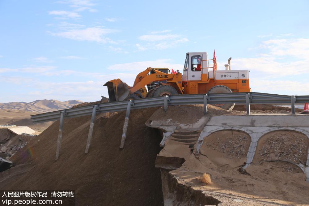 7月7日，甘肅省酒泉公路局機械在水毀路段填筑路基。