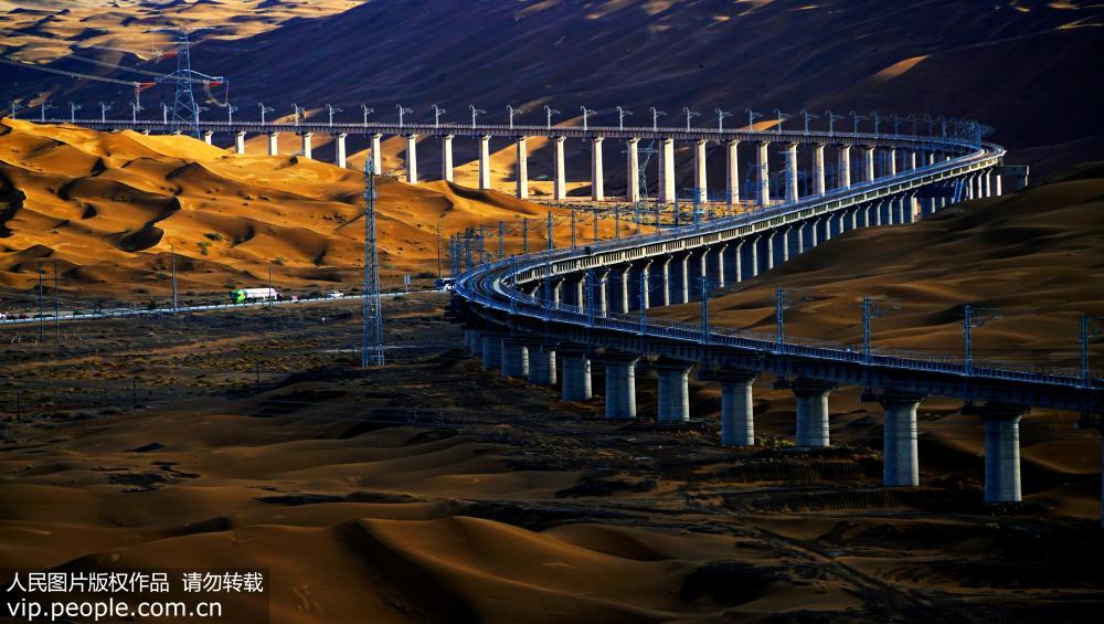 7月7日，雨后的敦格铁路沙山沟特大桥在光影的渲染下犹如一条蛟龙穿行在沙漠中。