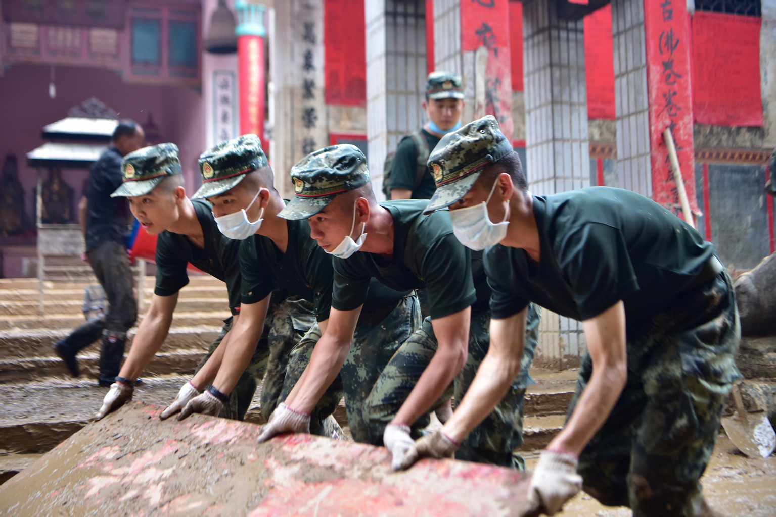 武警赣州支队官兵在江西省瑞金市九堡镇菜市场合力清理淤泥（7月20日摄）。