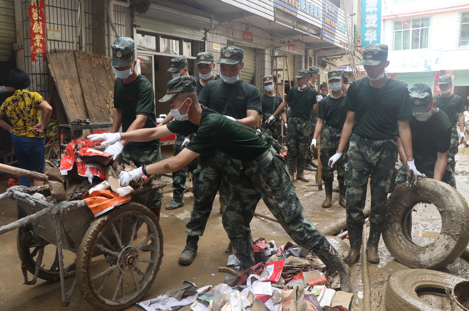 武警贛州支隊官兵在江西省瑞金市九堡鎮菜市場合力清理淤泥和垃圾（7月19日攝）。