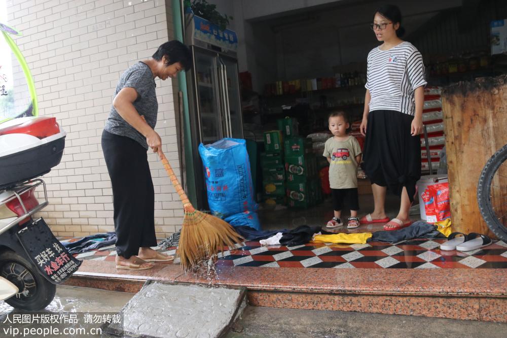 7月22日，在廈門市海滄區貞岱村，商戶在洪水回落后清理門店前的泥沙。