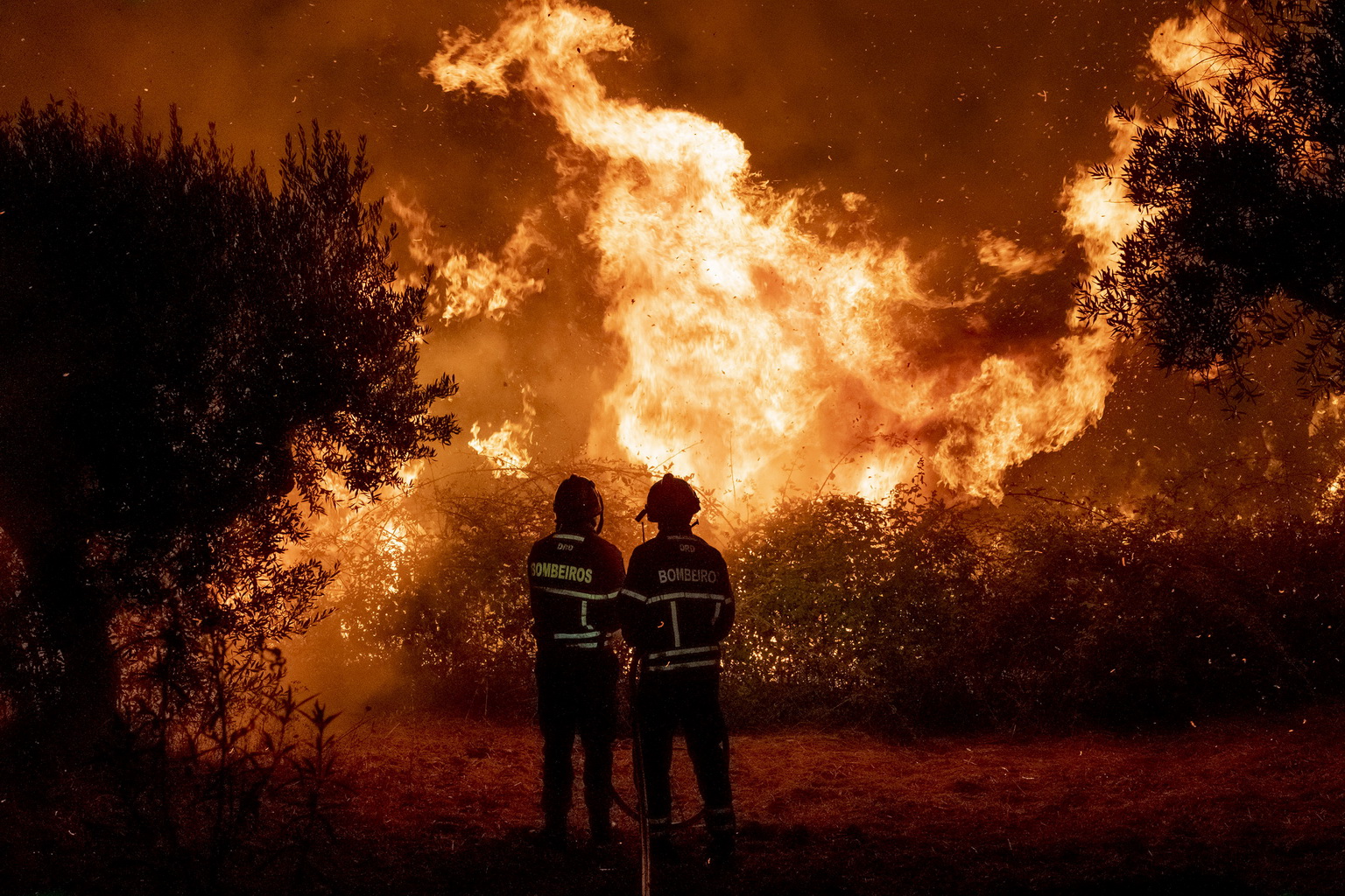 7月21日，在葡萄牙中部的卡爾迪古什村外，兩名消防人員在火場作業。
