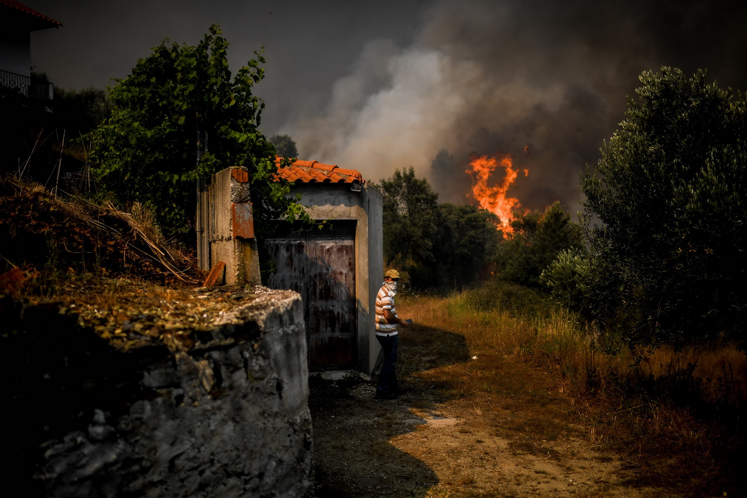 7月21日，在葡萄牙中部的羅達村，一名村民站在房屋前。