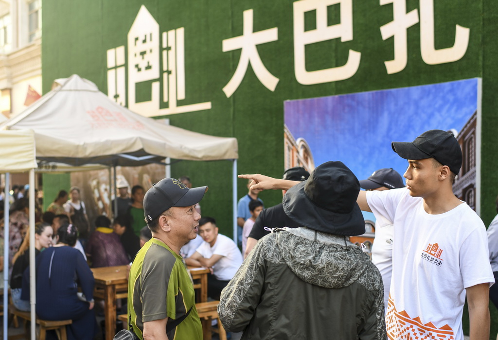 7月24日，志願者蘇巴提·蘇裡唐（右一）在大巴扎景區解答游客的咨詢。