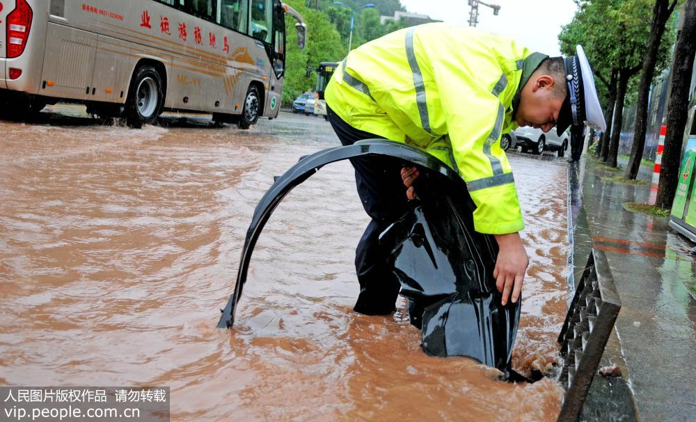 7月30日，一名交警在疏通道路上的下水道。