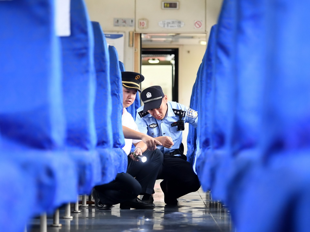 7月31日，守車列車長徐波（左）與重慶鐵路公安處民警在硬座車廂內檢查列車隱蔽部位。