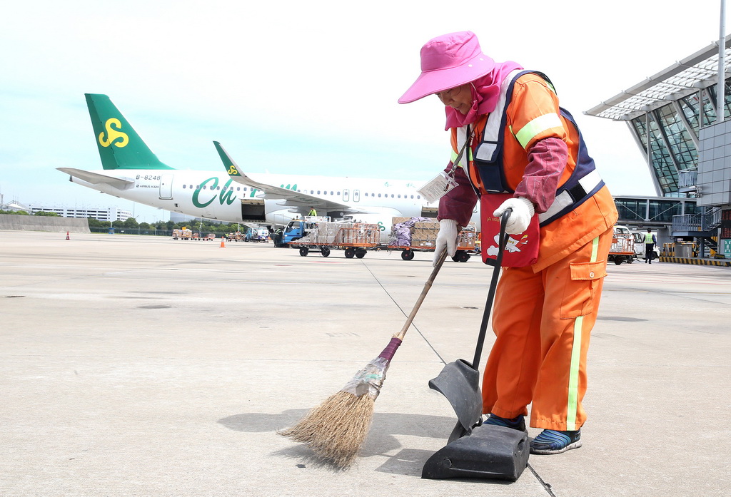 7月31日，機場保潔員秦彩芳在上海浦東國際機場停機坪進行保潔作業。