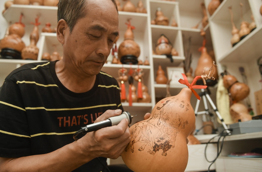 8月4日，王洪淼在家中進行烙畫葫蘆創作。