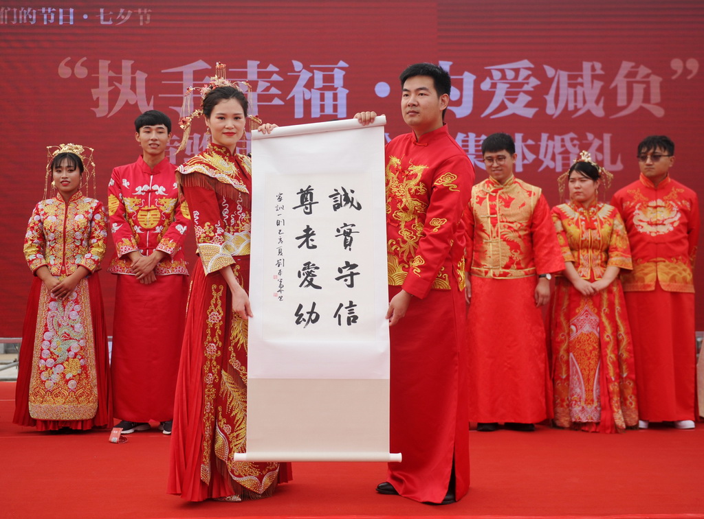 8月6日，在河北黃驊南海公園舉辦的“執手幸福·為愛減負”大型公益集體婚禮上，一對新人展示家風家訓書法作品。