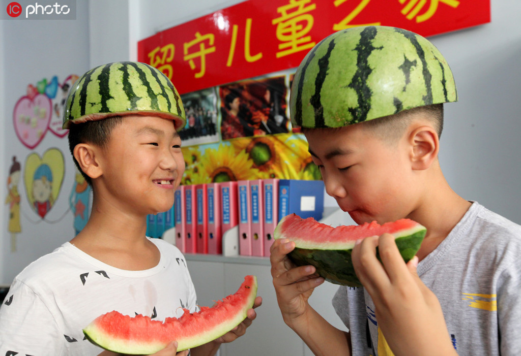 8月7日，在枣庄市公安局市中分局永安派出所社区民警创办的“留守儿童之家”，两名小朋友头戴“西瓜帽”在吃西瓜“啃秋”。