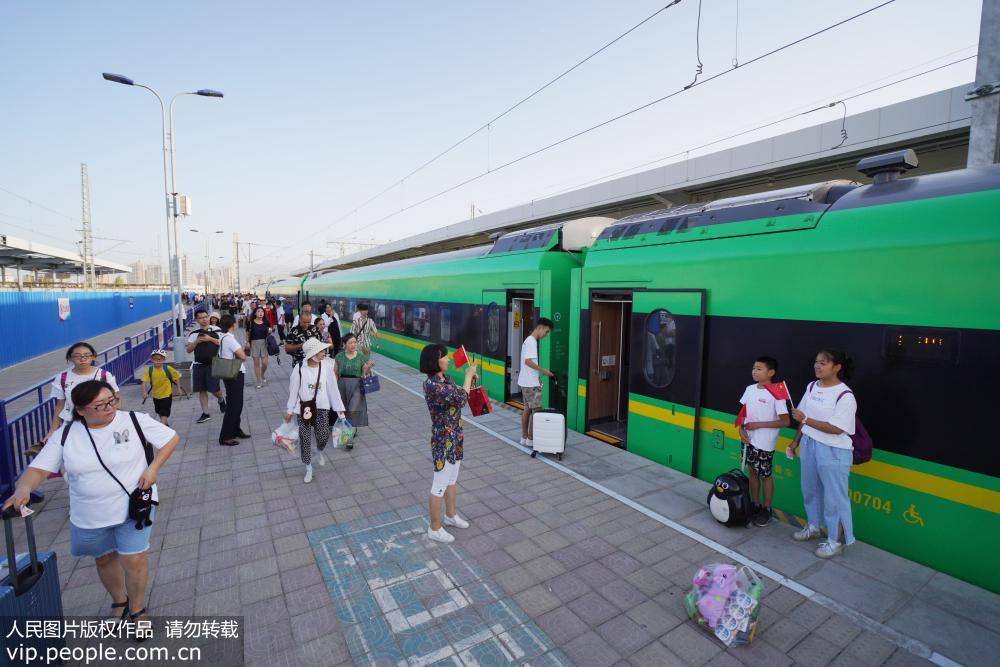 8月8日，在庫爾勒火車站，乘客提著行李正准備登上駛向烏魯木齊的“復興號”列車。