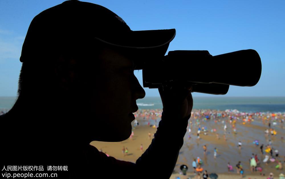 8月3日，江蘇省連雲港市連島海濱浴場，救生員在固定瞭望台用望遠鏡巡視四方，游人的動態盡收眼底。
